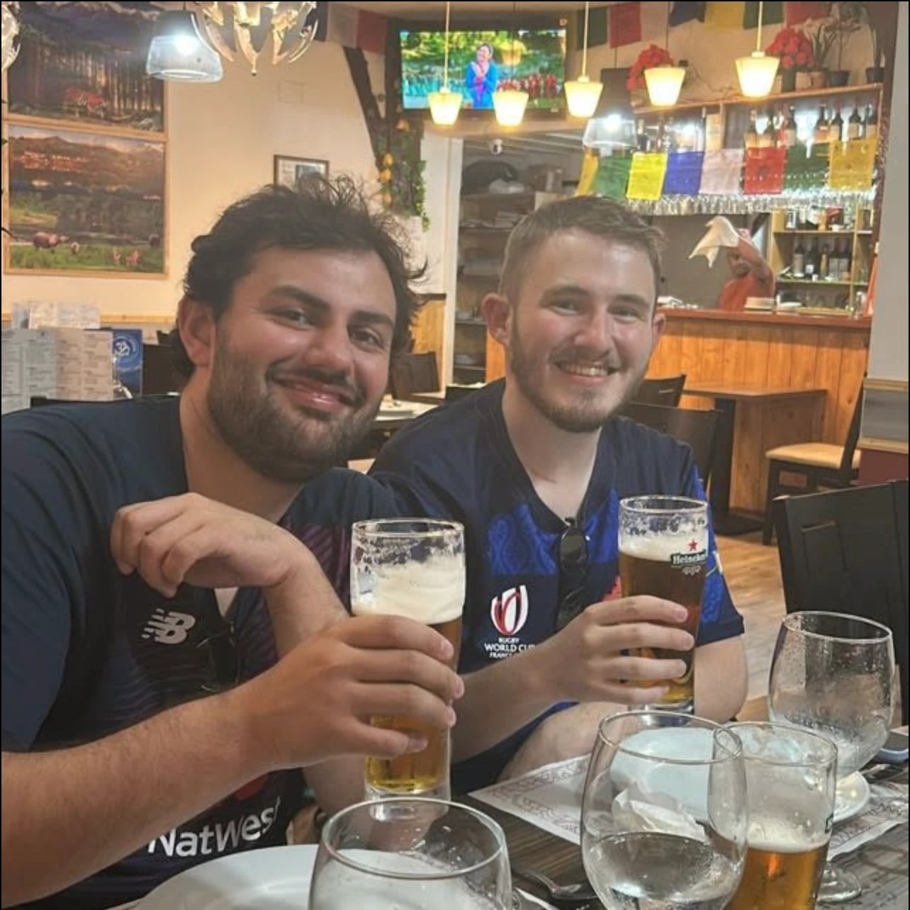 William Nijjer, left, and a friend raising beers at a restaurant table