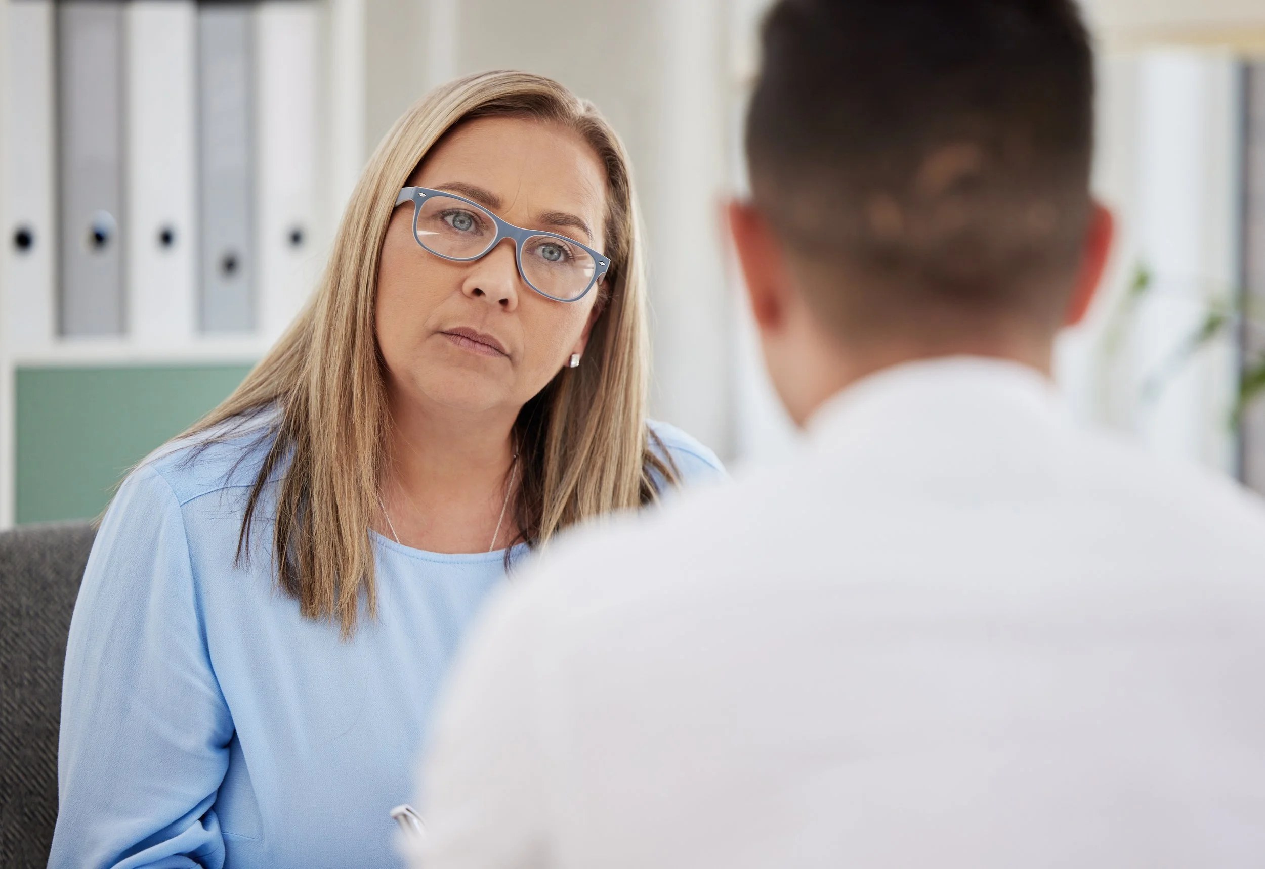 A female patient standing up to her doctor.